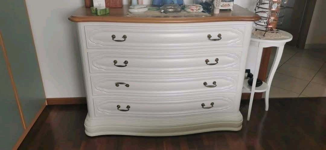 Una cassettiera bianca è appoggiata sul pavimento di legno in una stanza.