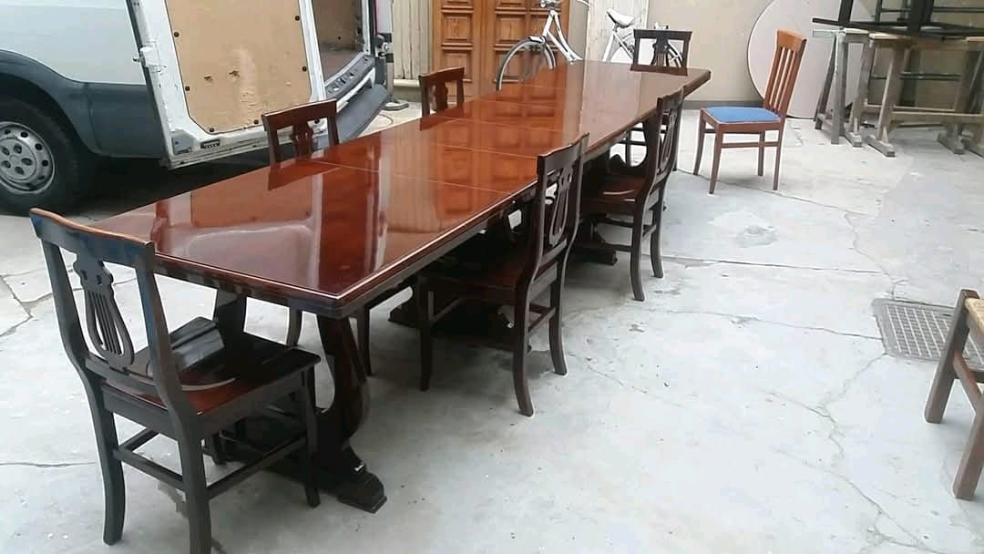 Un lungo tavolo di legno con sedie e un furgone sullo sfondo