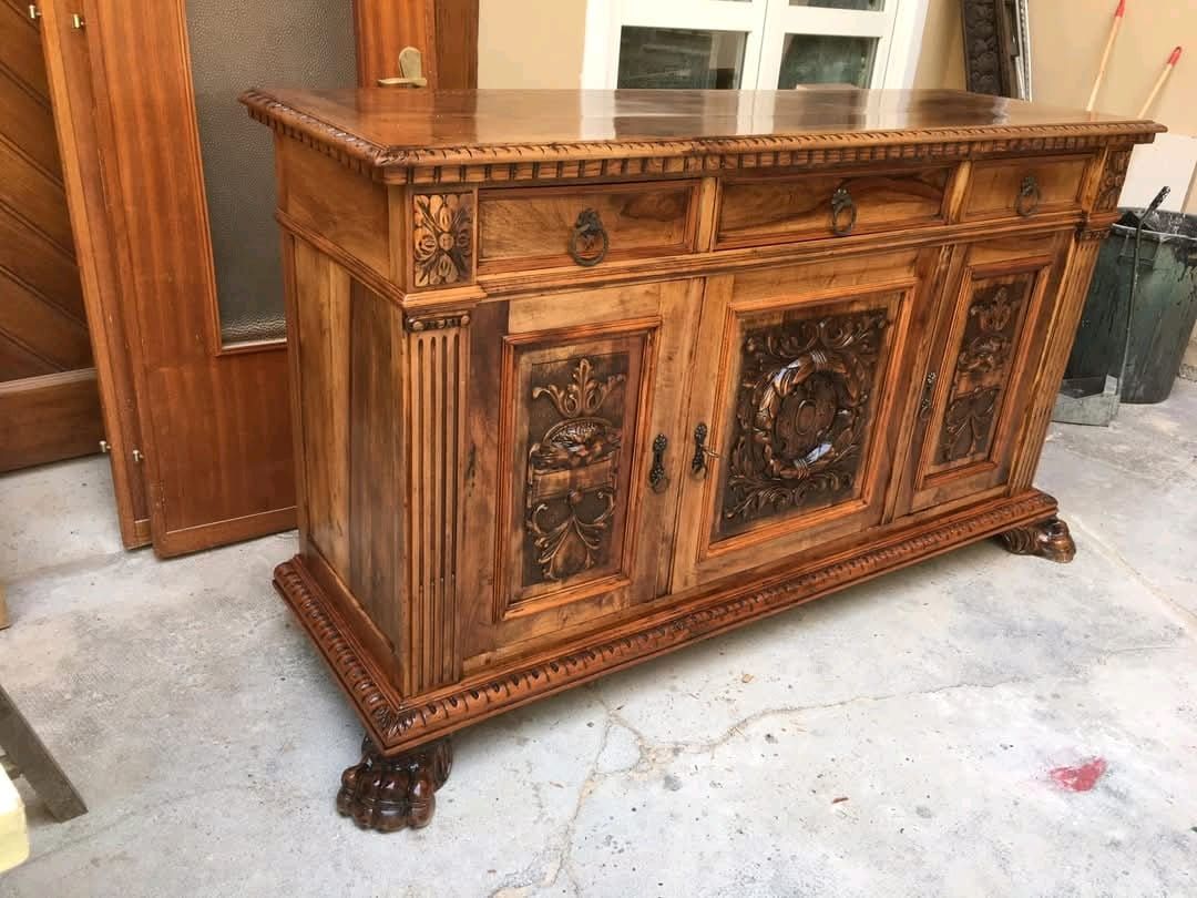 Un mobiletto di legno con cassetti e ante è appoggiato su un pavimento di cemento.