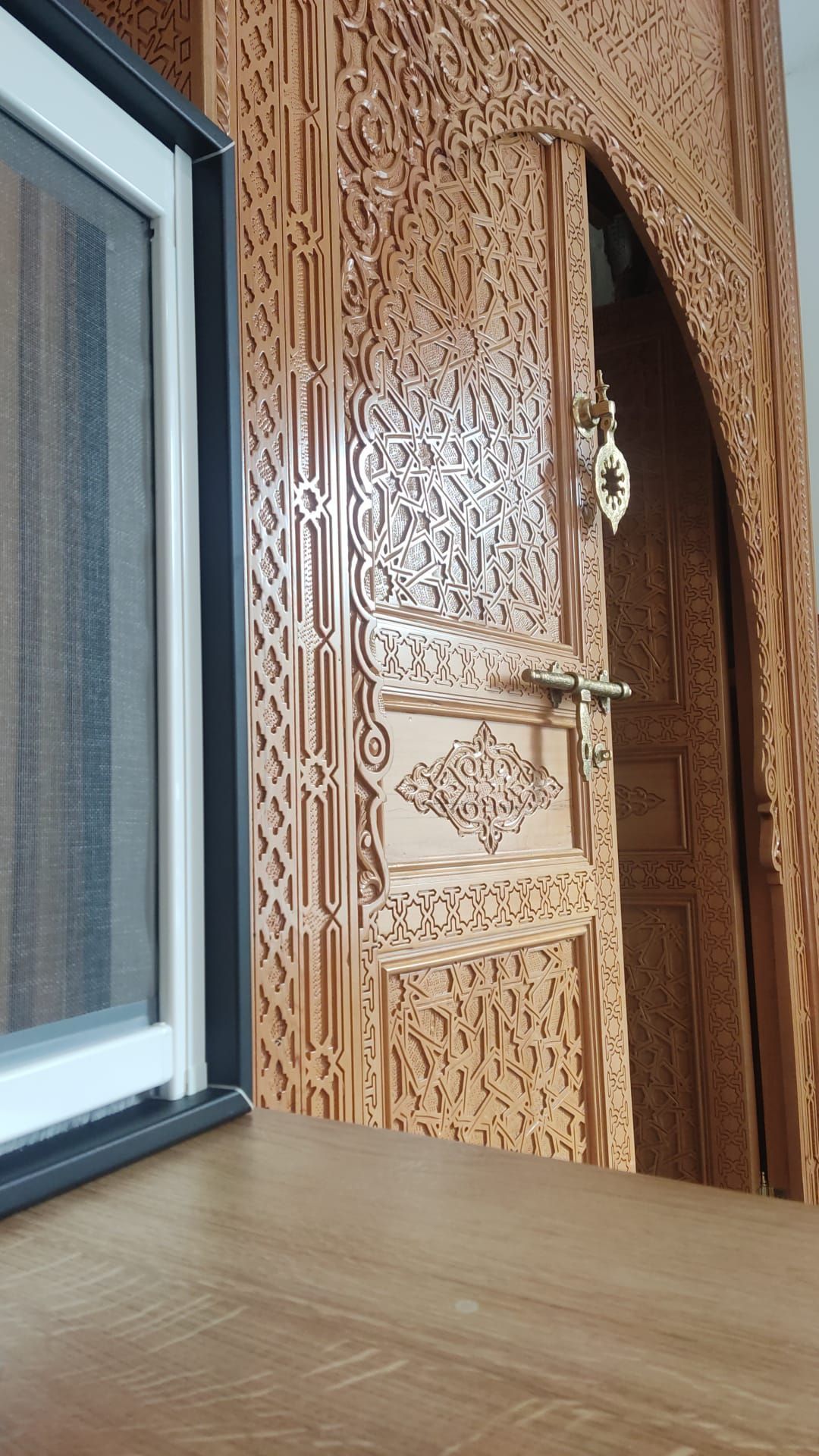 Una porta di legno con un motivo è accanto a una finestra.