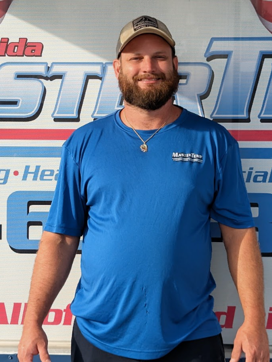 Man in blue shirt and cap standing in front of a branded event backdrop