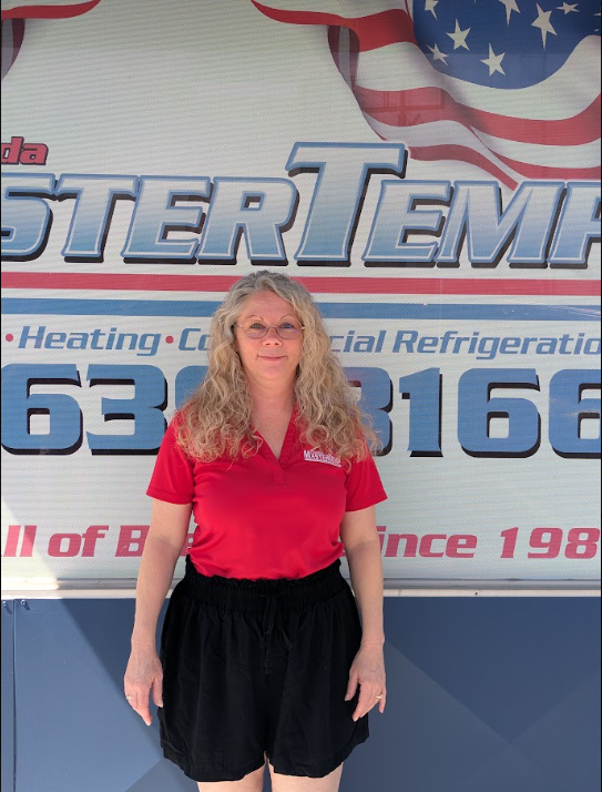 Woman in red shirt and black shorts standing in front of a company banner outdoors