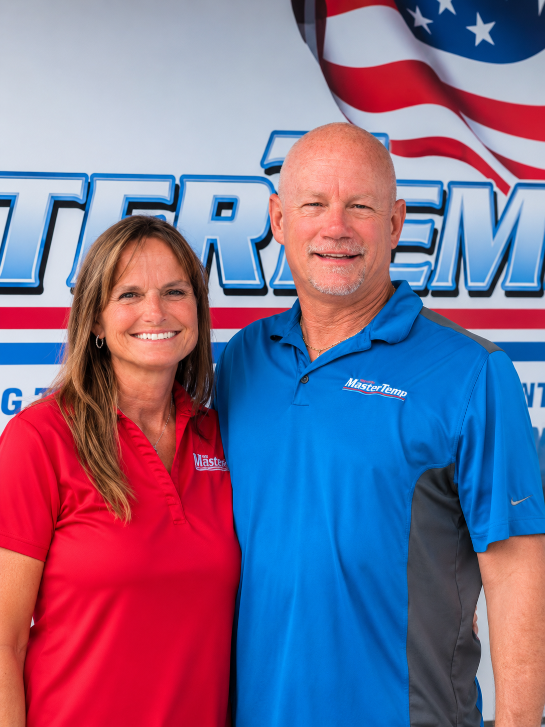 Two smiling people in red and blue polos standing in front of a patriotic backdrop