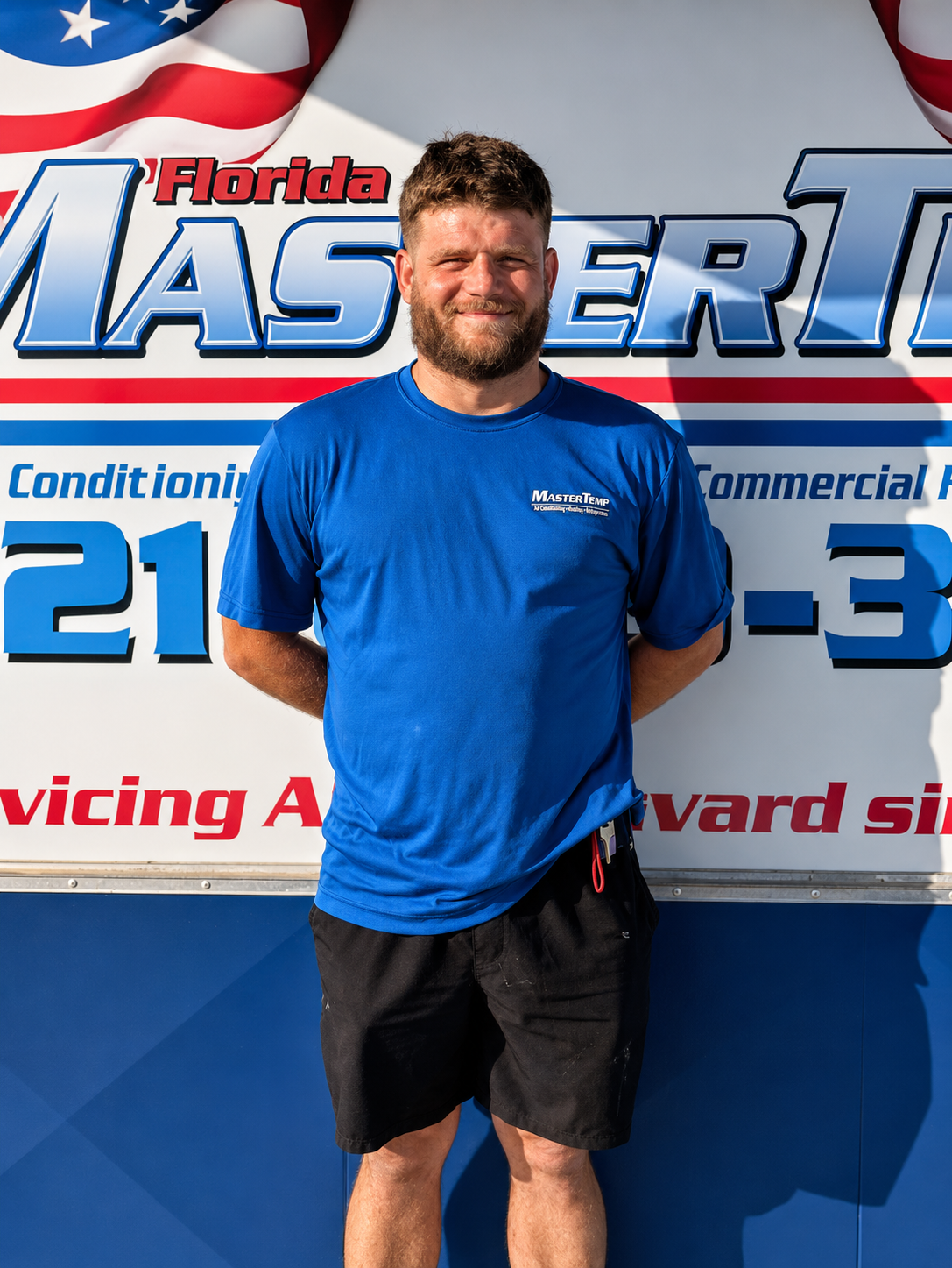 Man in blue shirt standing in front of Florida Master T sign and service vehicle backdrop