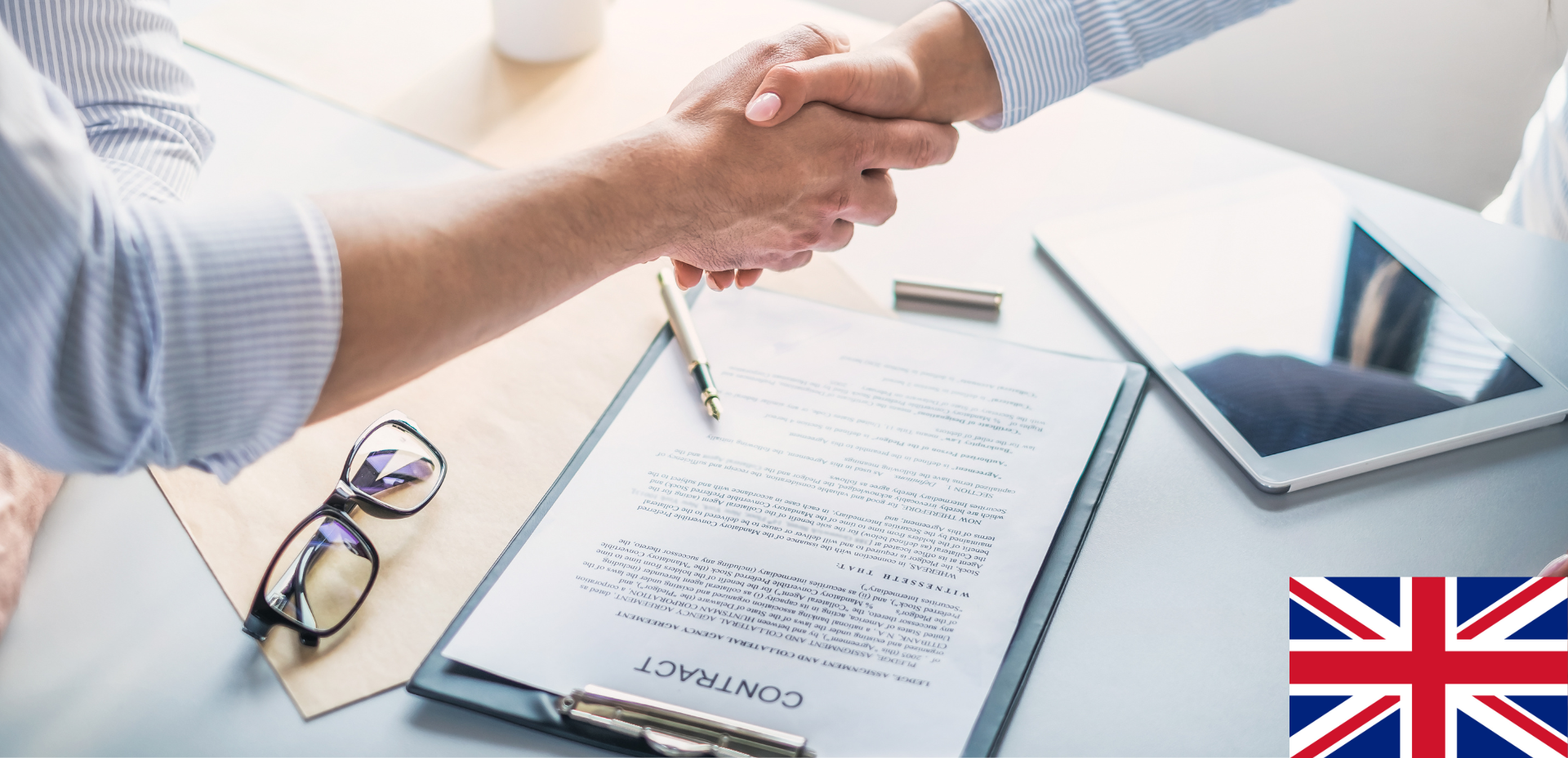Twee mensen schudden elkaar de hand over een contract. De Britse vlag in de hoek.