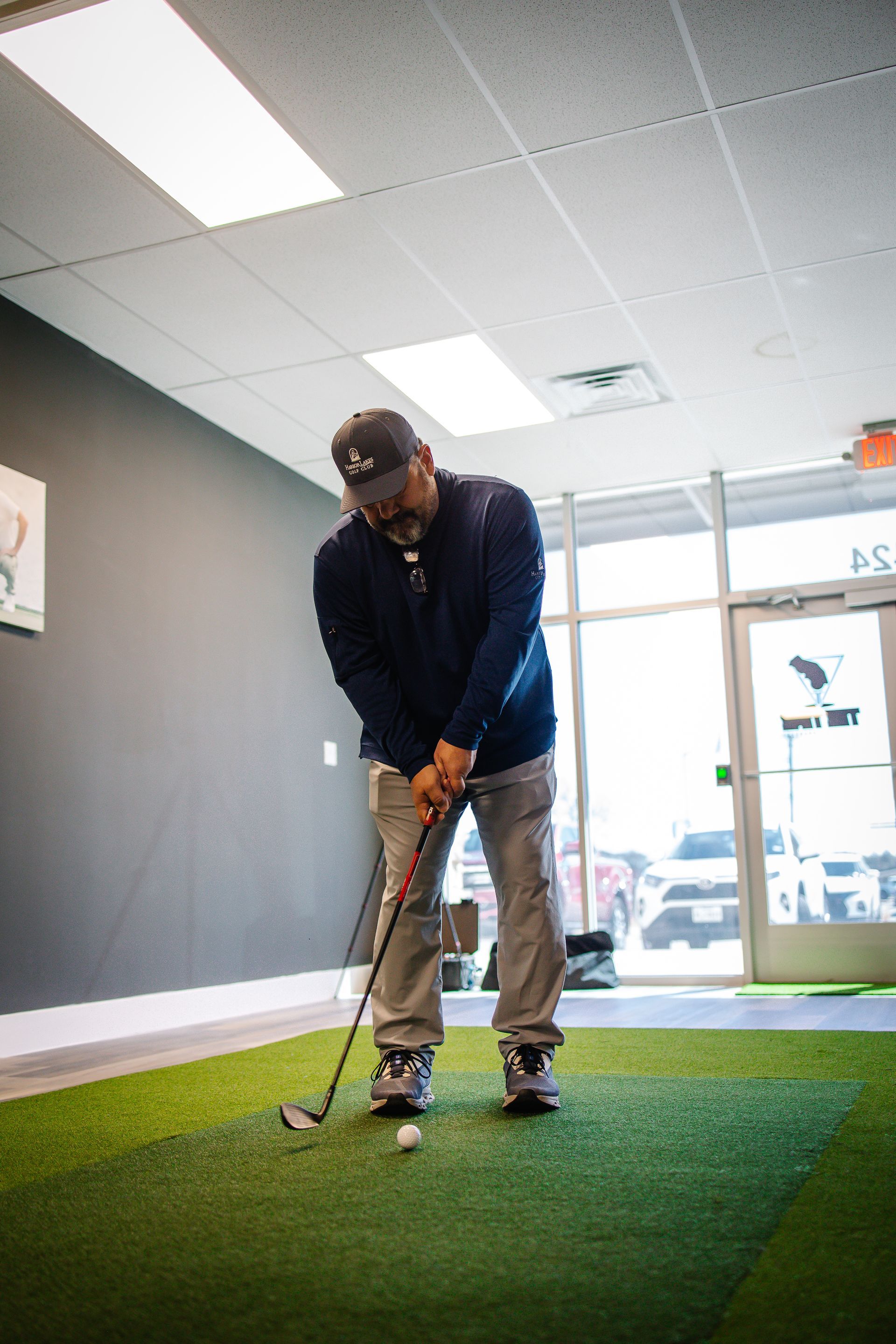 A man is swinging a golf club at a golf ball in a room.