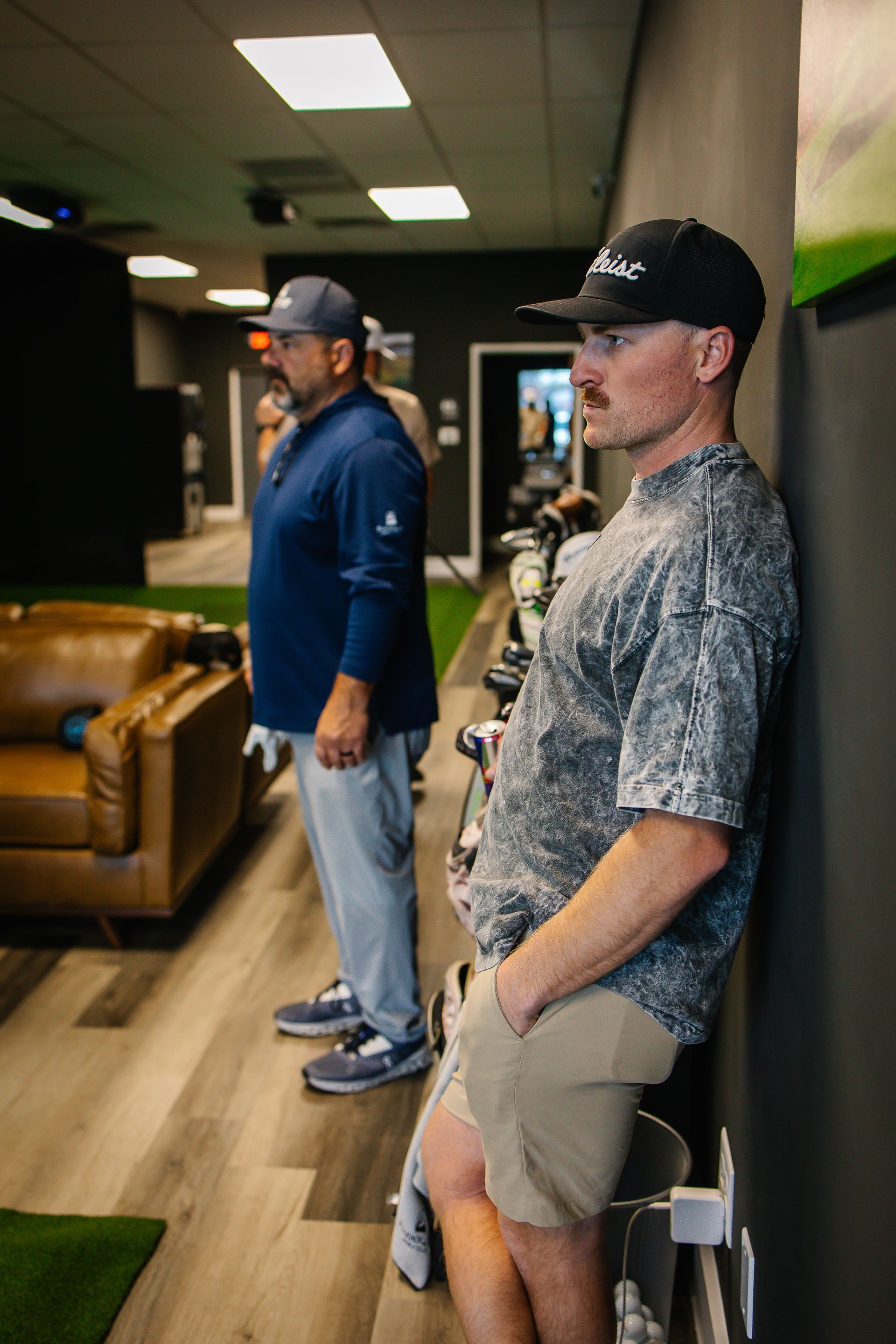 Two men are leaning against a wall in a room.
