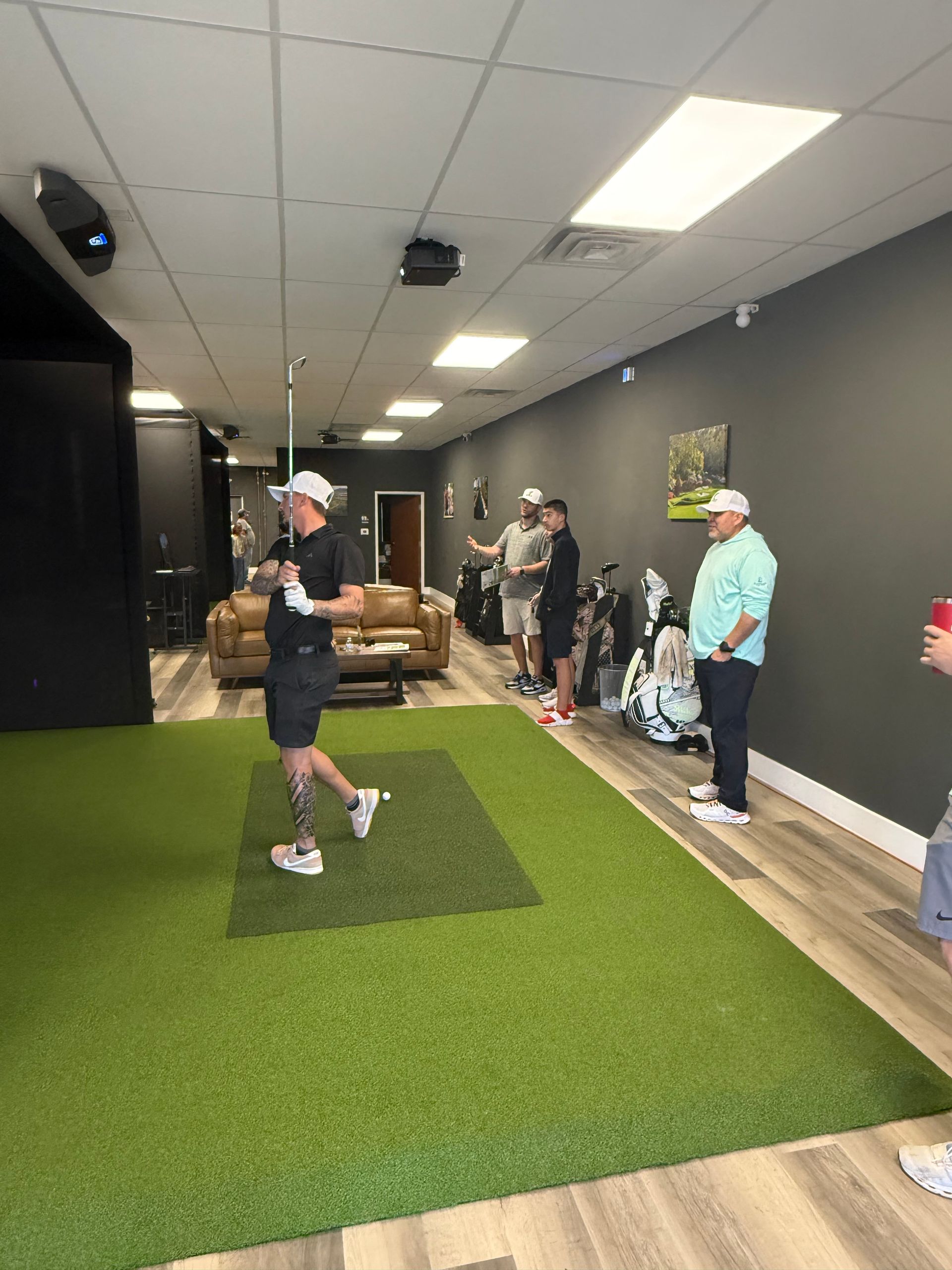 A group of people are standing in a room playing golf.