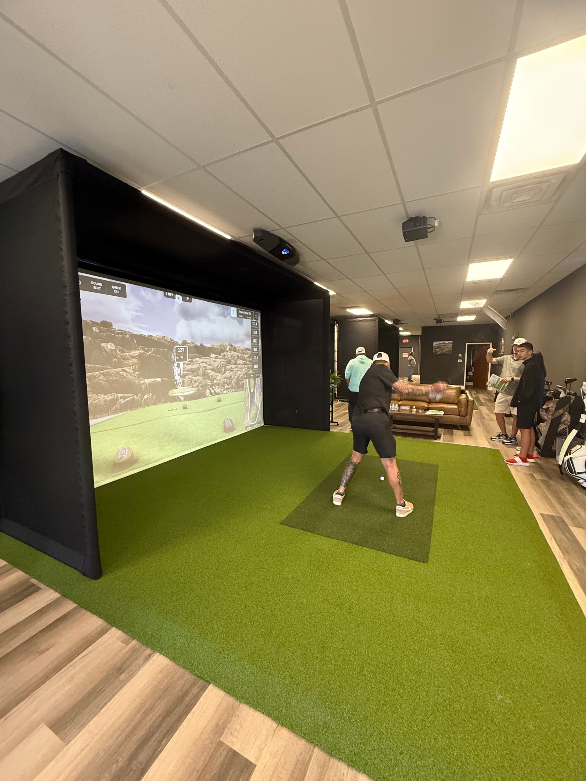 A man is playing golf in a simulator in a living room.