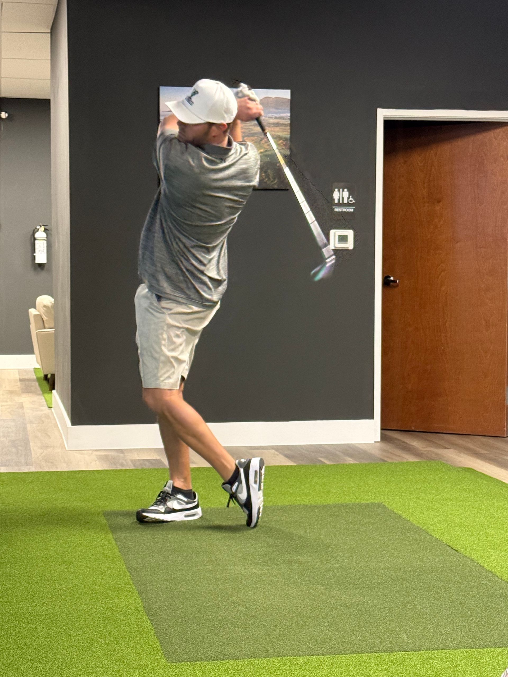 A man is swinging a golf club in a room.