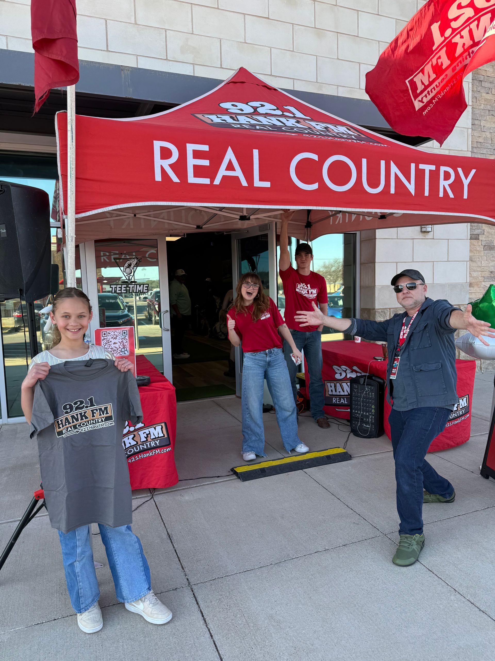 A group of people standing under a tent that says real country