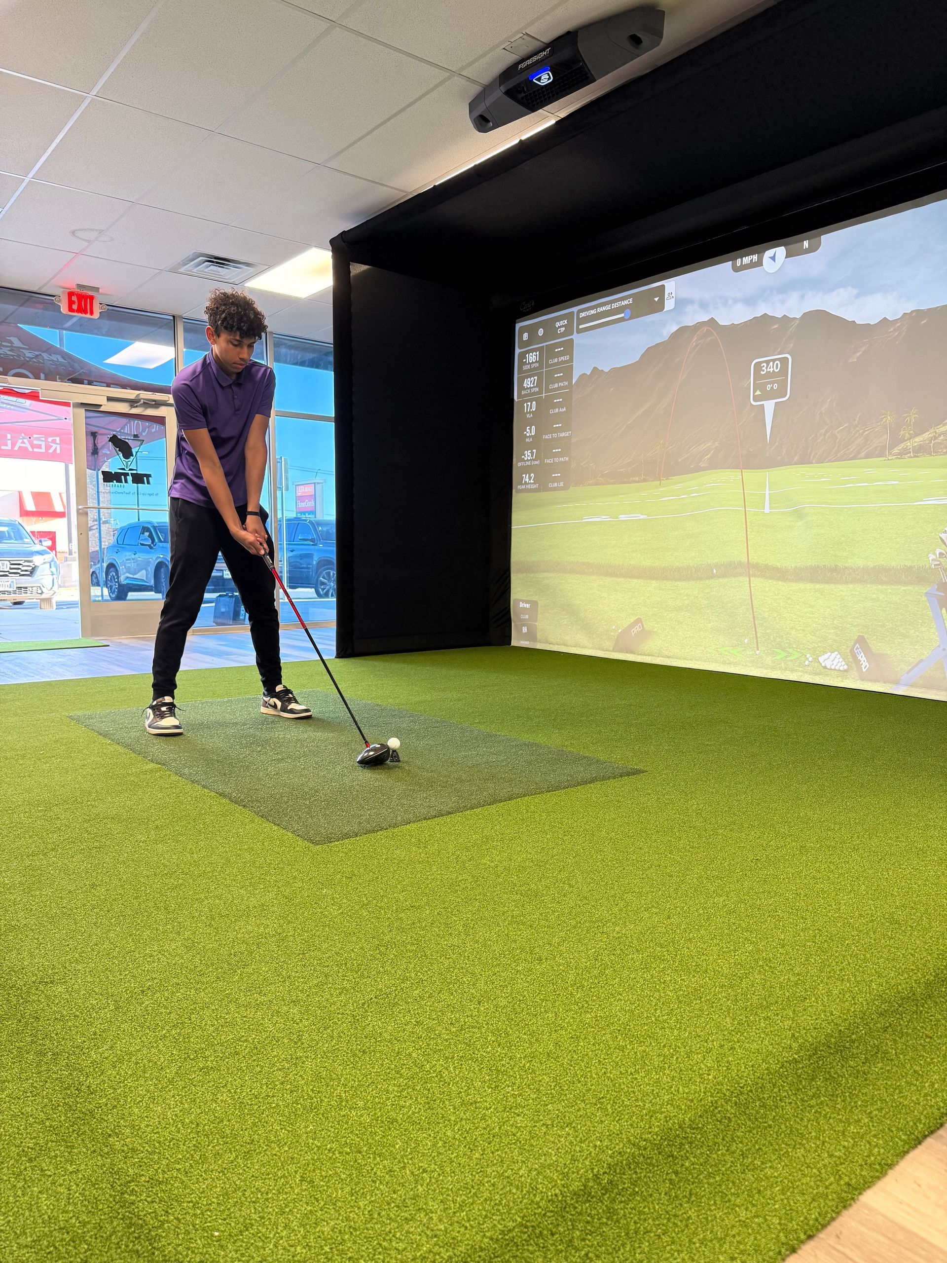 A man is swinging a golf club in a golf simulator.