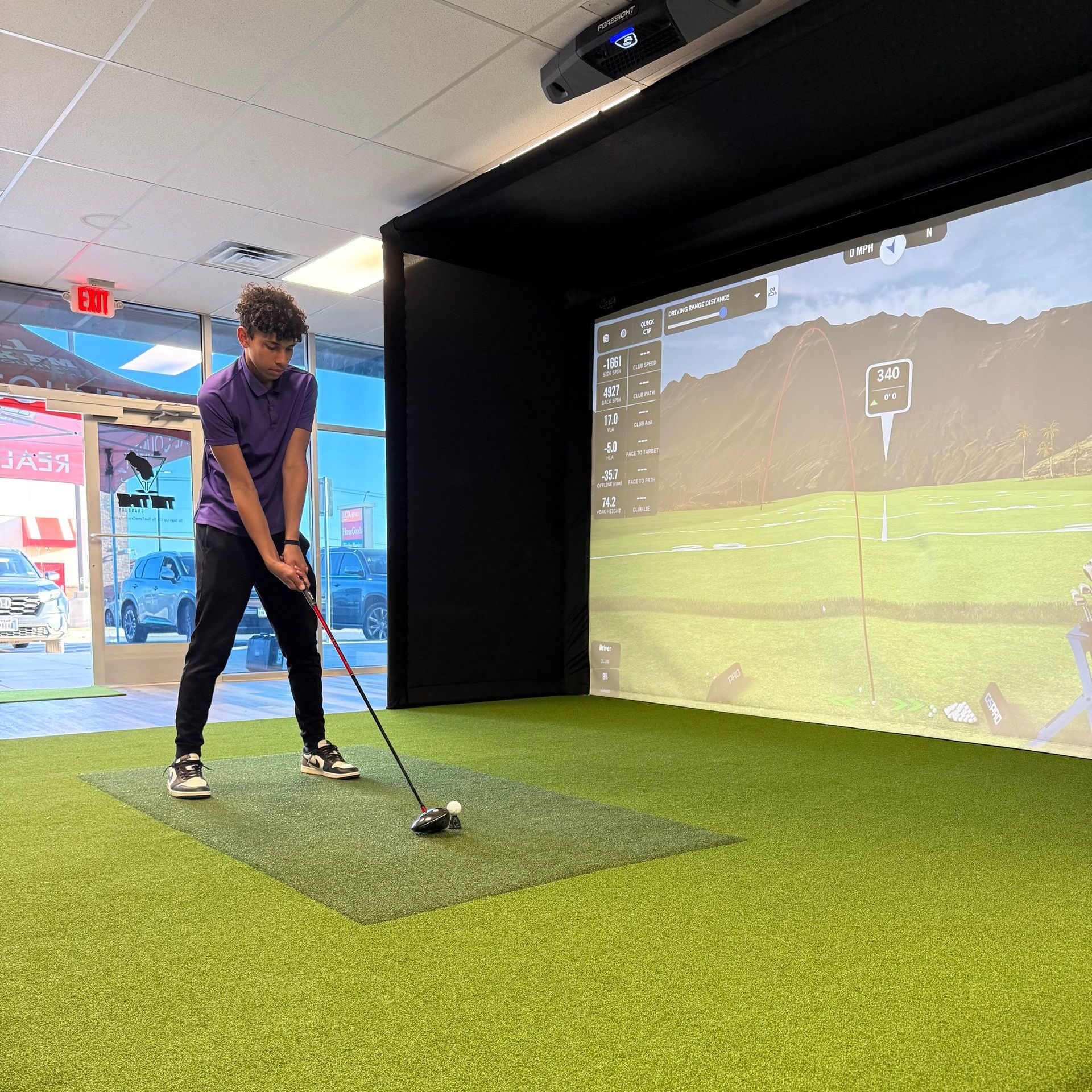 A man is swinging a golf club in a simulator