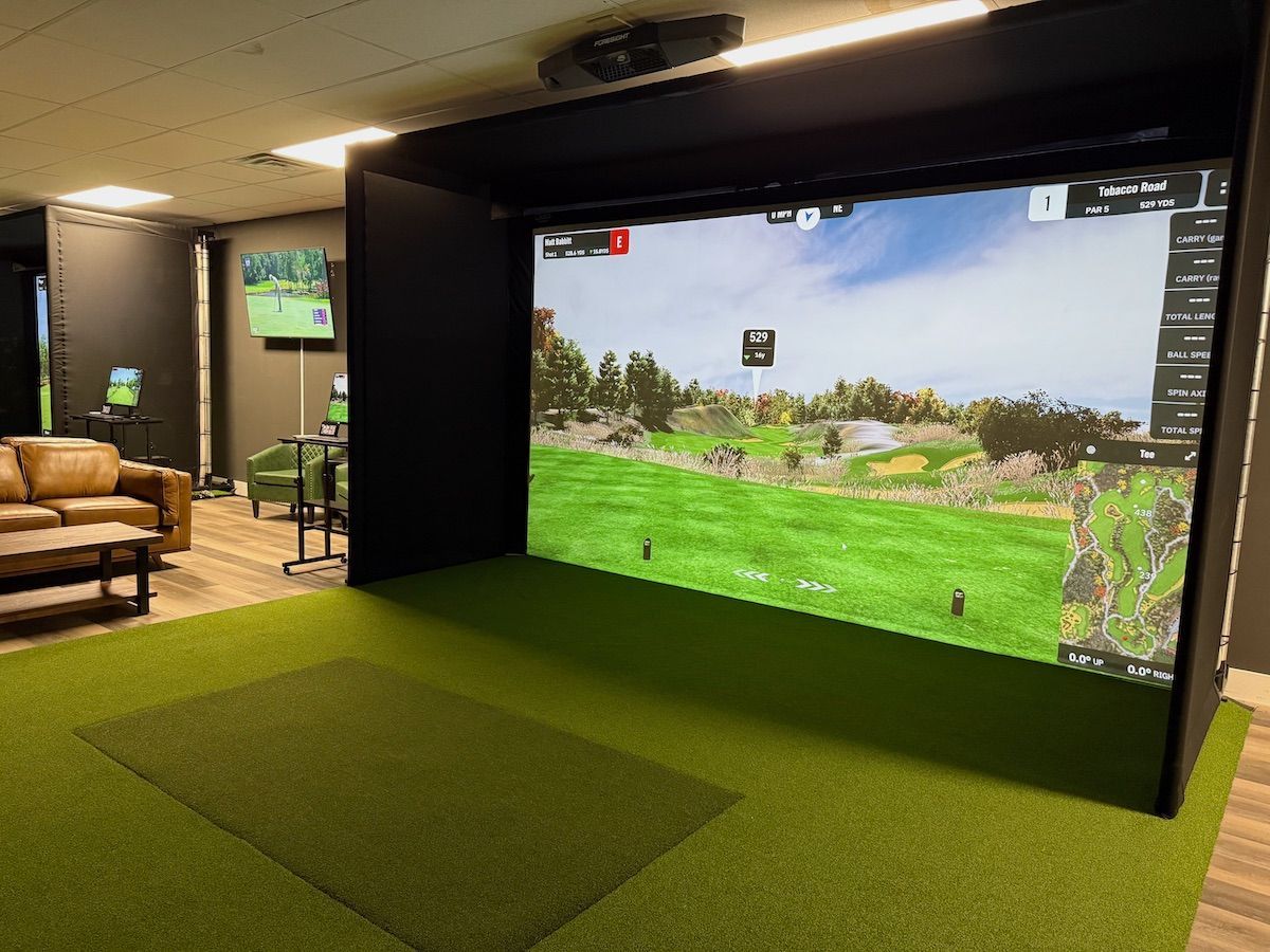 A golf simulator in a living room with a large screen.