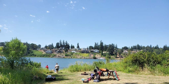 A group of people are sitting at a picnic table near a lake.