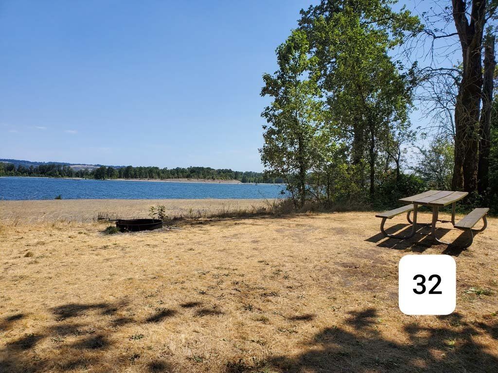 A picnic table is sitting on a sandy beach next to a lake.