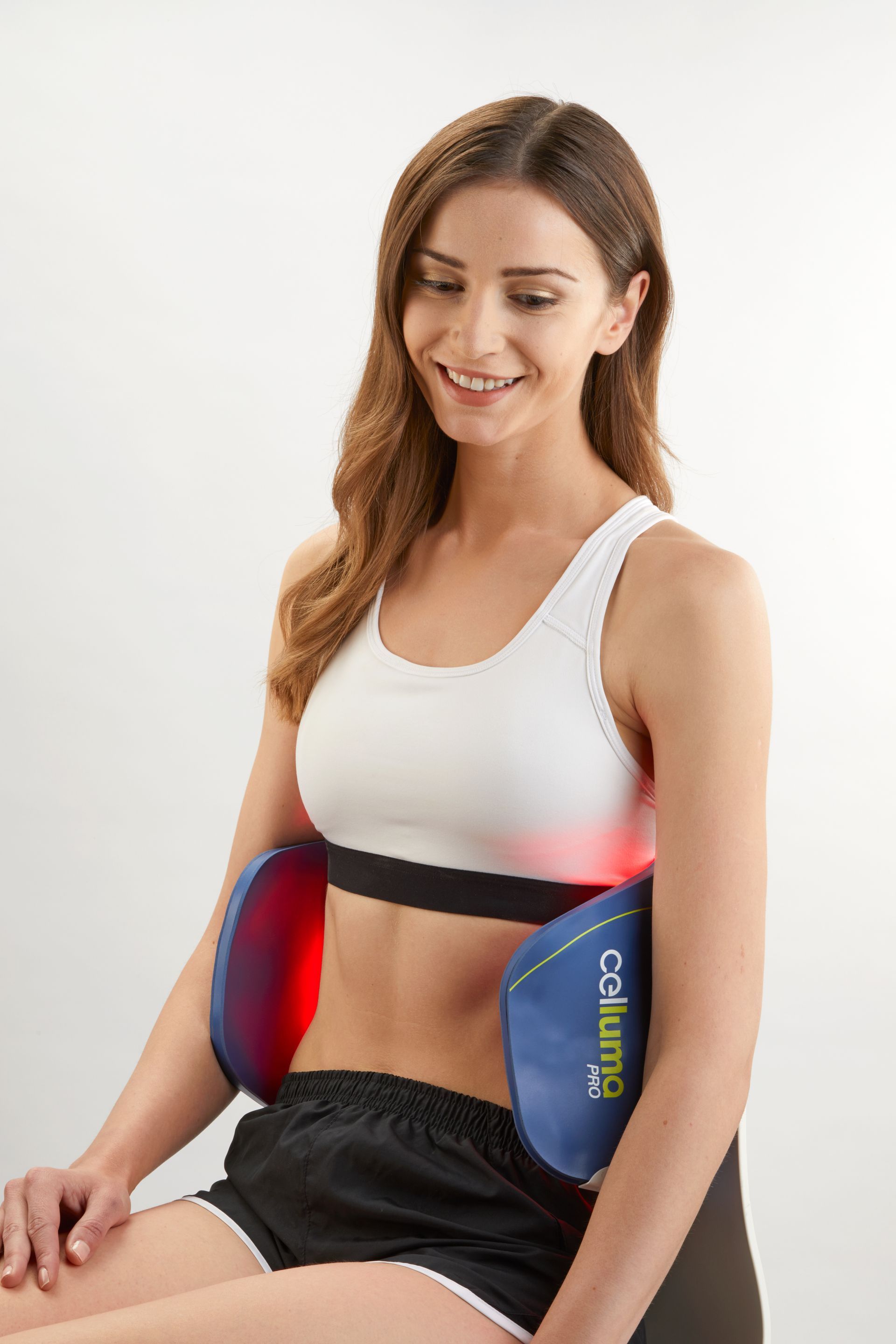 A woman is sitting on a chair with a device on her stomach