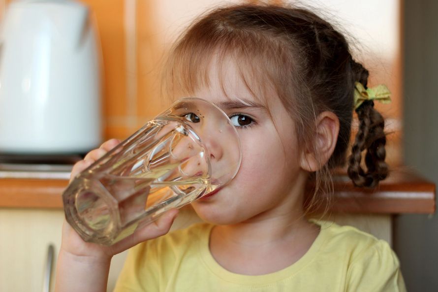 Primo piano di macchinari industriali con tubi, valvole e un serbatoio metallico in un ambiente di fabbrica.