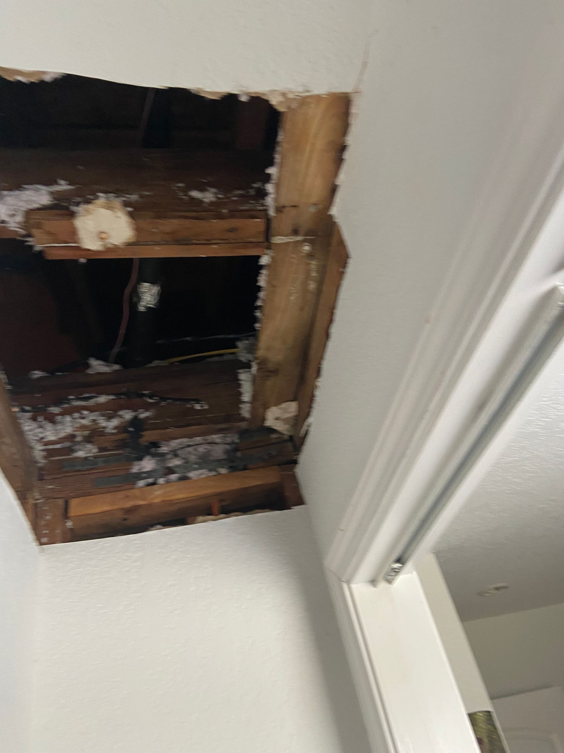 A hole in the ceiling of a room with a door.