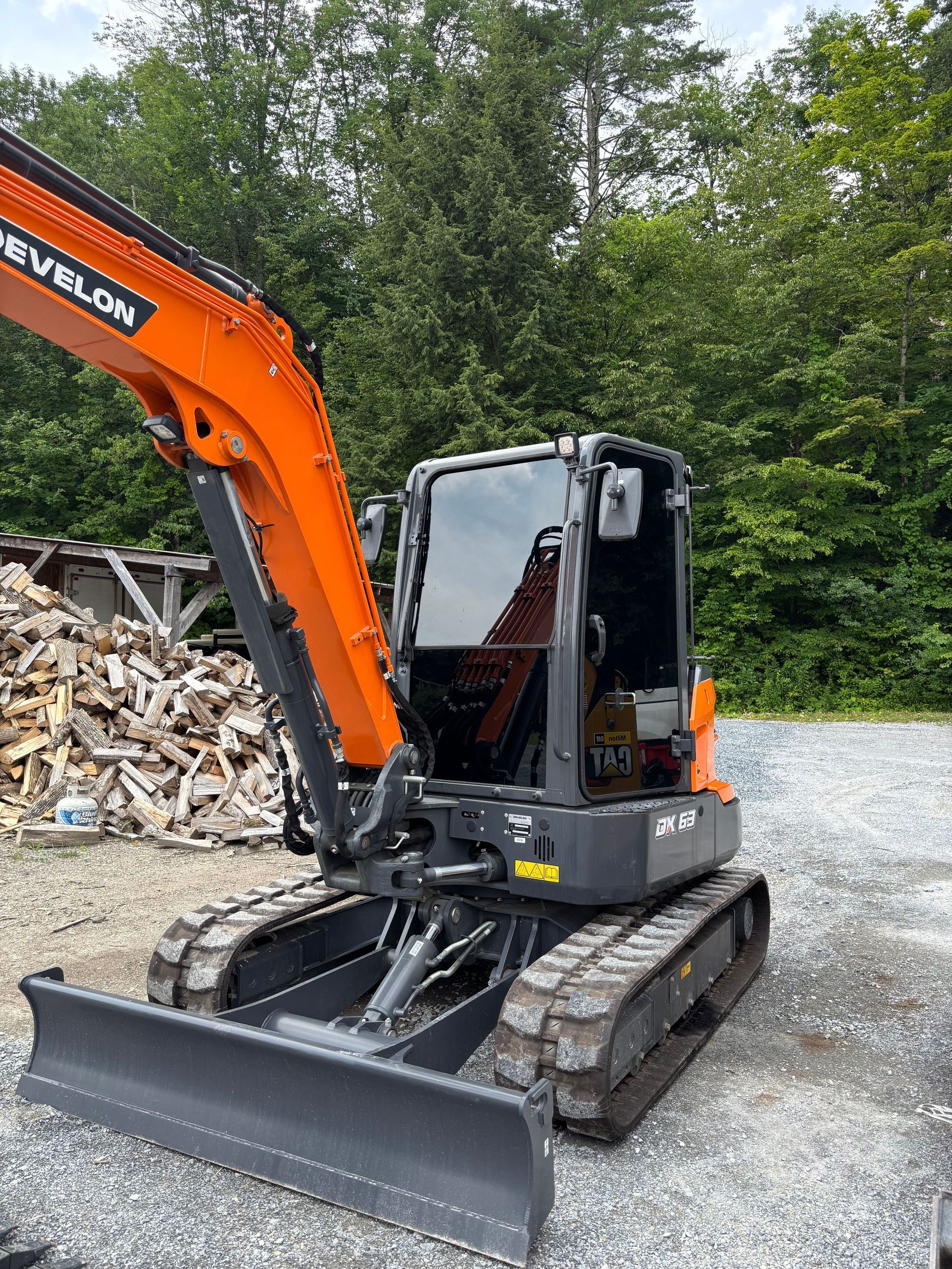 A person on a ladder is working on a large, blue vehicle panel inside a garage.