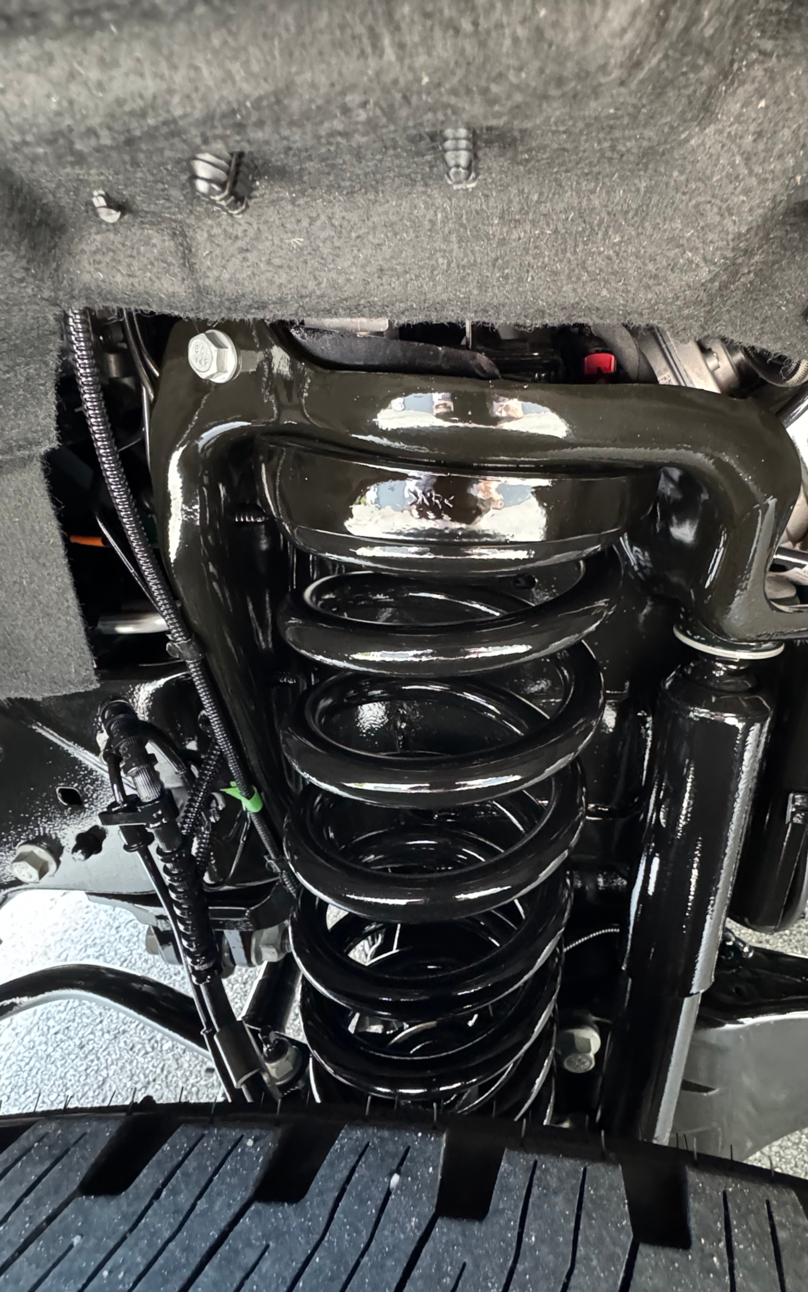 Black suspension assembly of a vehicle, including spring, shock absorber, and support structure.