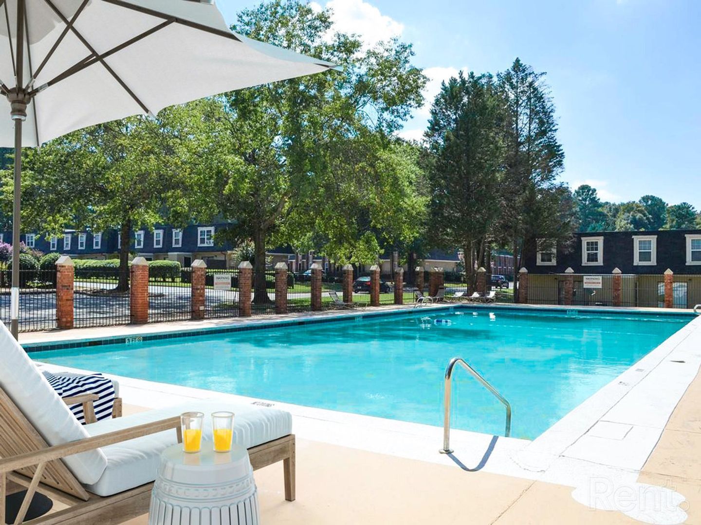 Pool with white umbrella and lounge chair; sunny day.