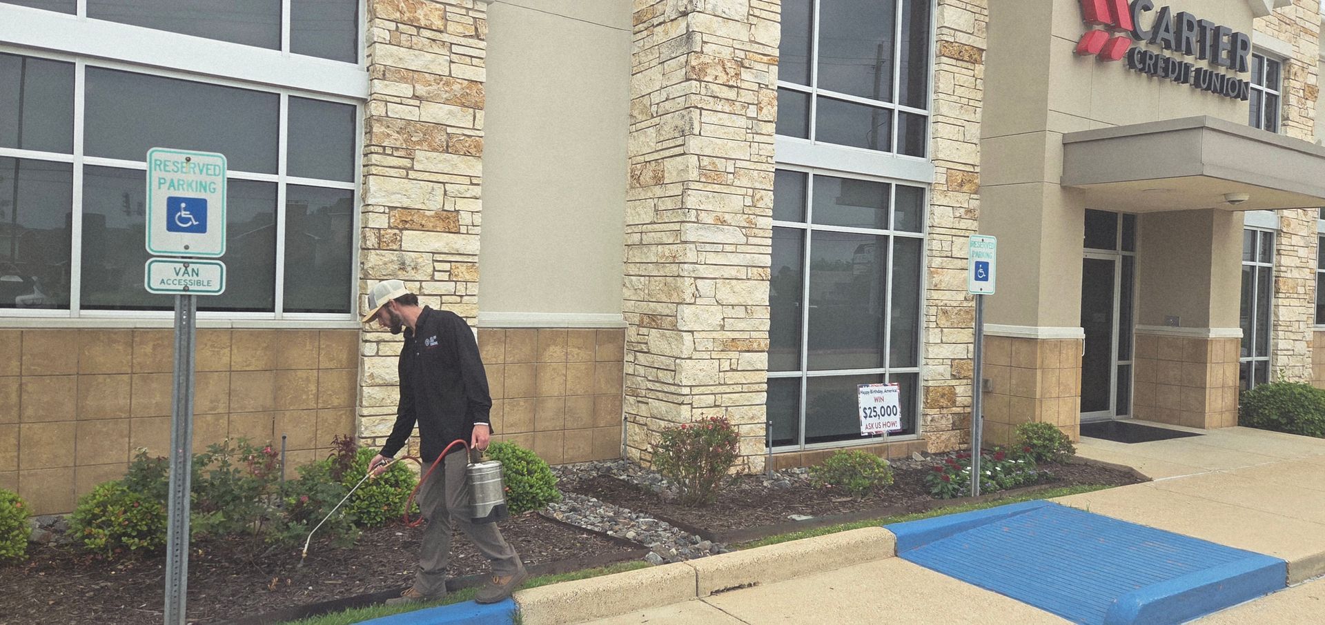 Person crouching by a building entrance, next to a handicap parking sign and blue curb ramp.