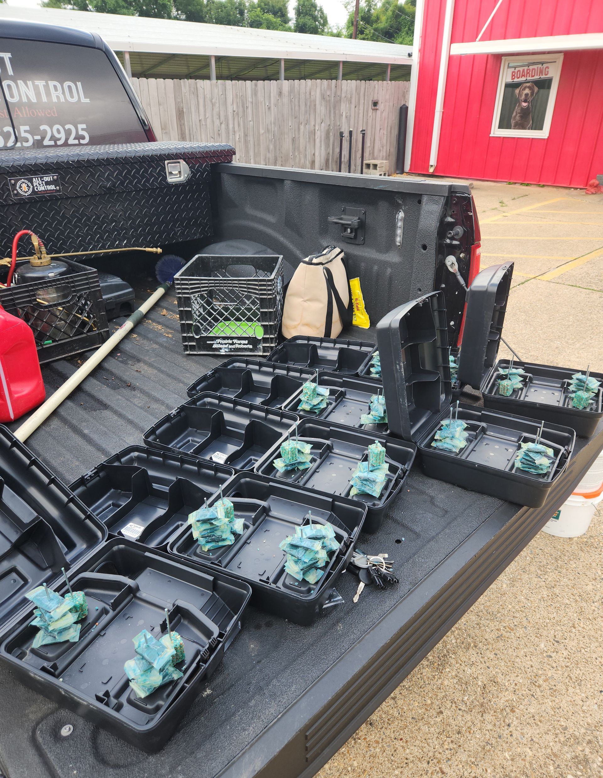 Open case of black electronic devices on a truck bed beside a red building