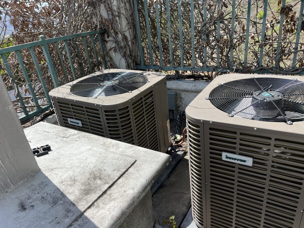 Two air conditioners are sitting next to each other on a balcony.