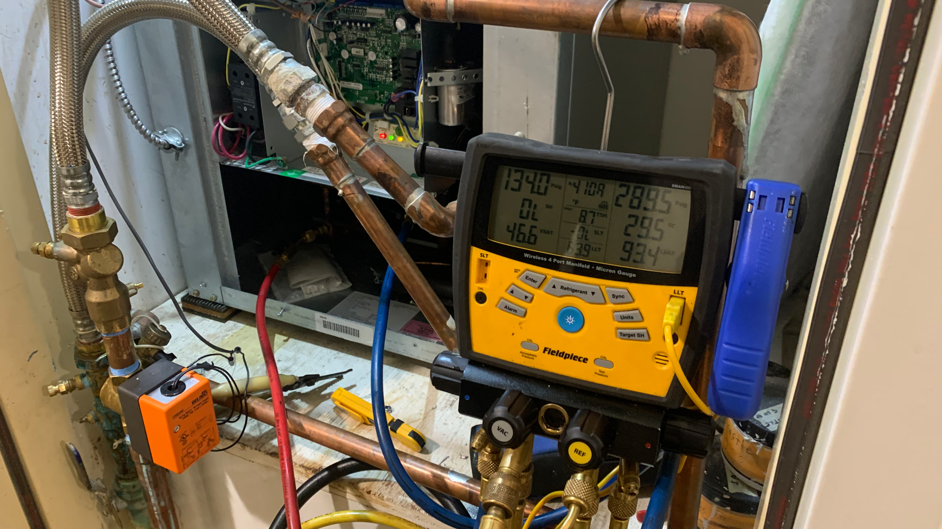 A digital thermometer is sitting on top of a copper pipe.