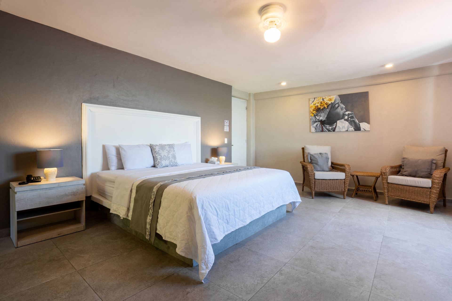 Dormitorio con cama king, mesitas de noche, zona de estar, colores neutros.