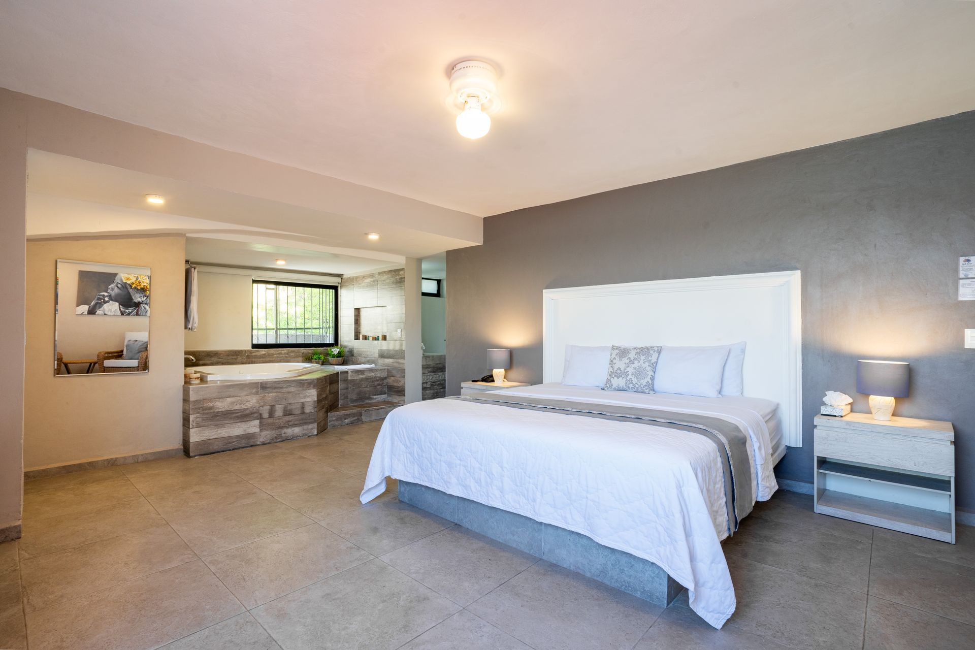 Dormitorio moderno con cama king, jacuzzi y decoración en gris y blanco.