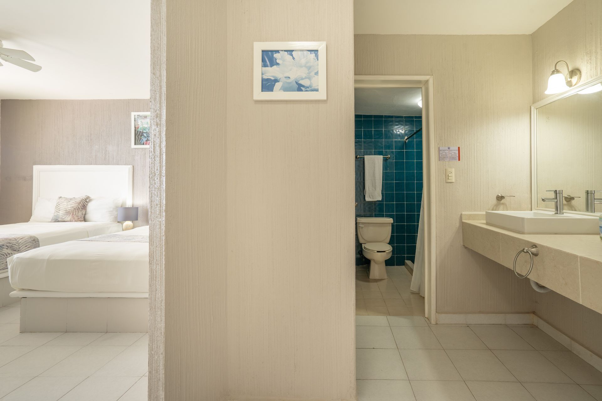 Interior de habitación de hotel: dormitorio con dos camas, baño con inodoro y lavabo.