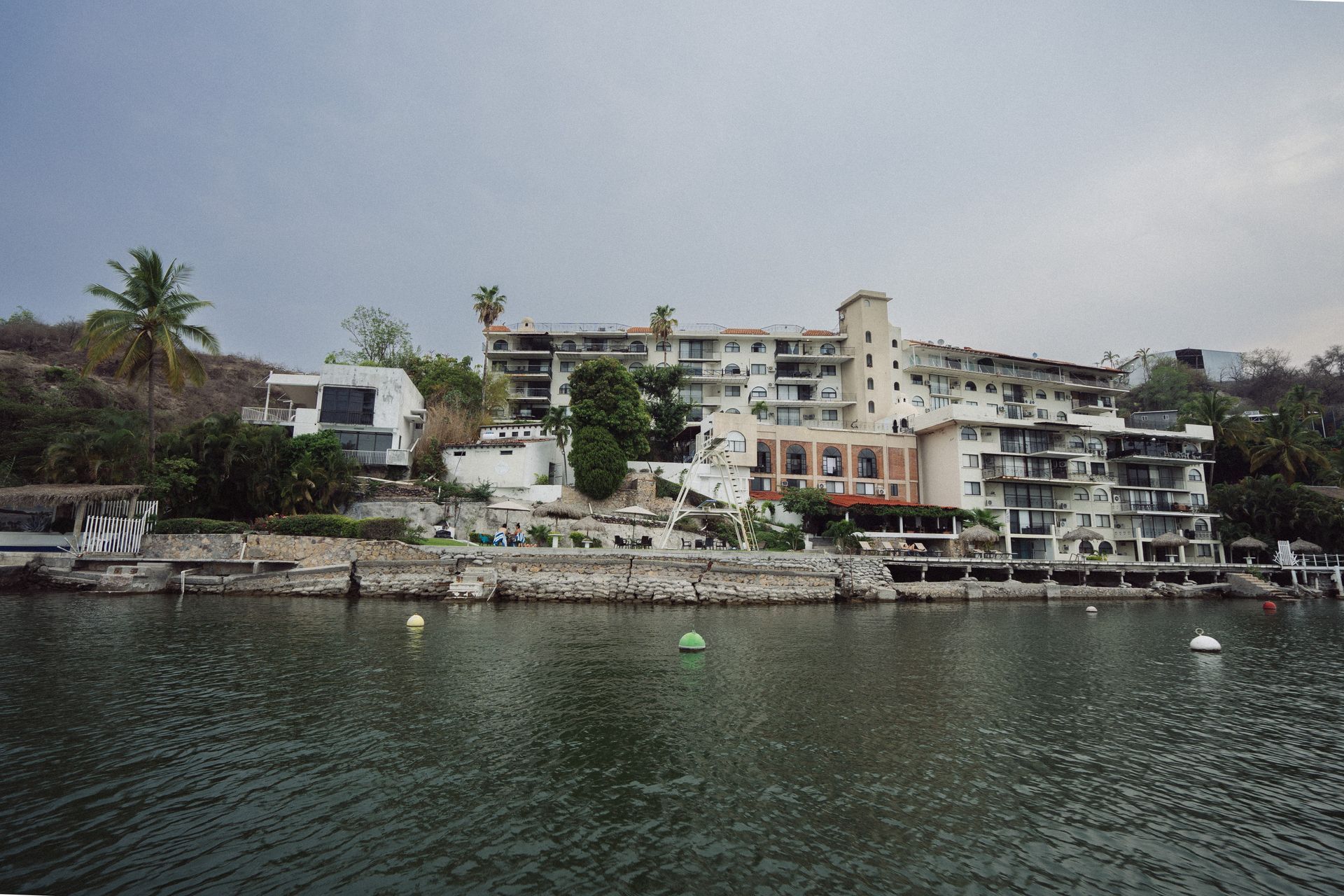 Edificios frente al mar, posiblemente condominios o apartamentos, bajo un cielo nublado.