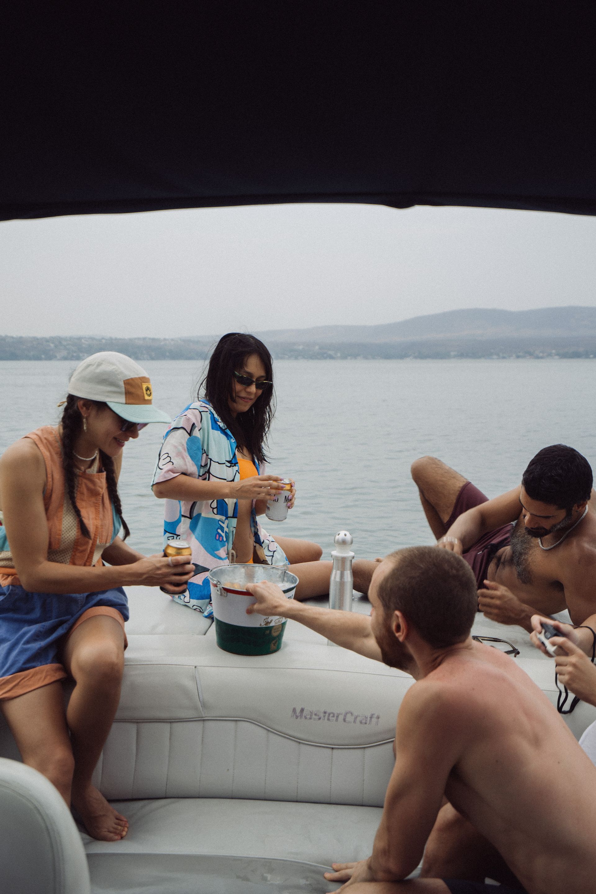 Gente en un barco, bebiendo y riendo. Día nublado en el agua.
