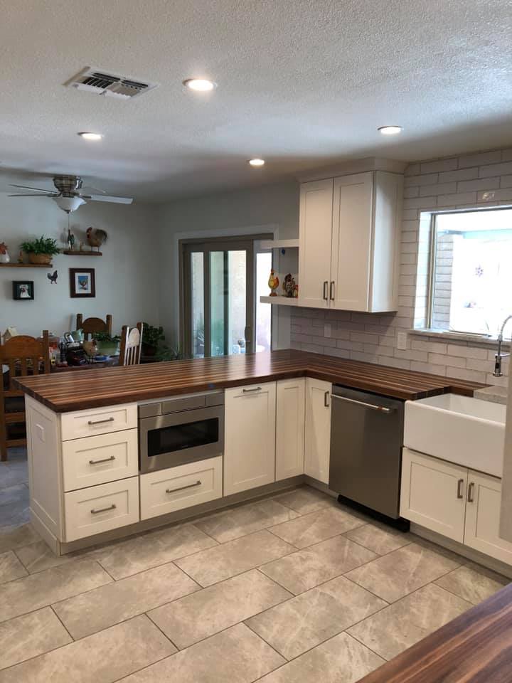 Modern kitchen with white cabinets, wood countertops, and stainless steel appliances.