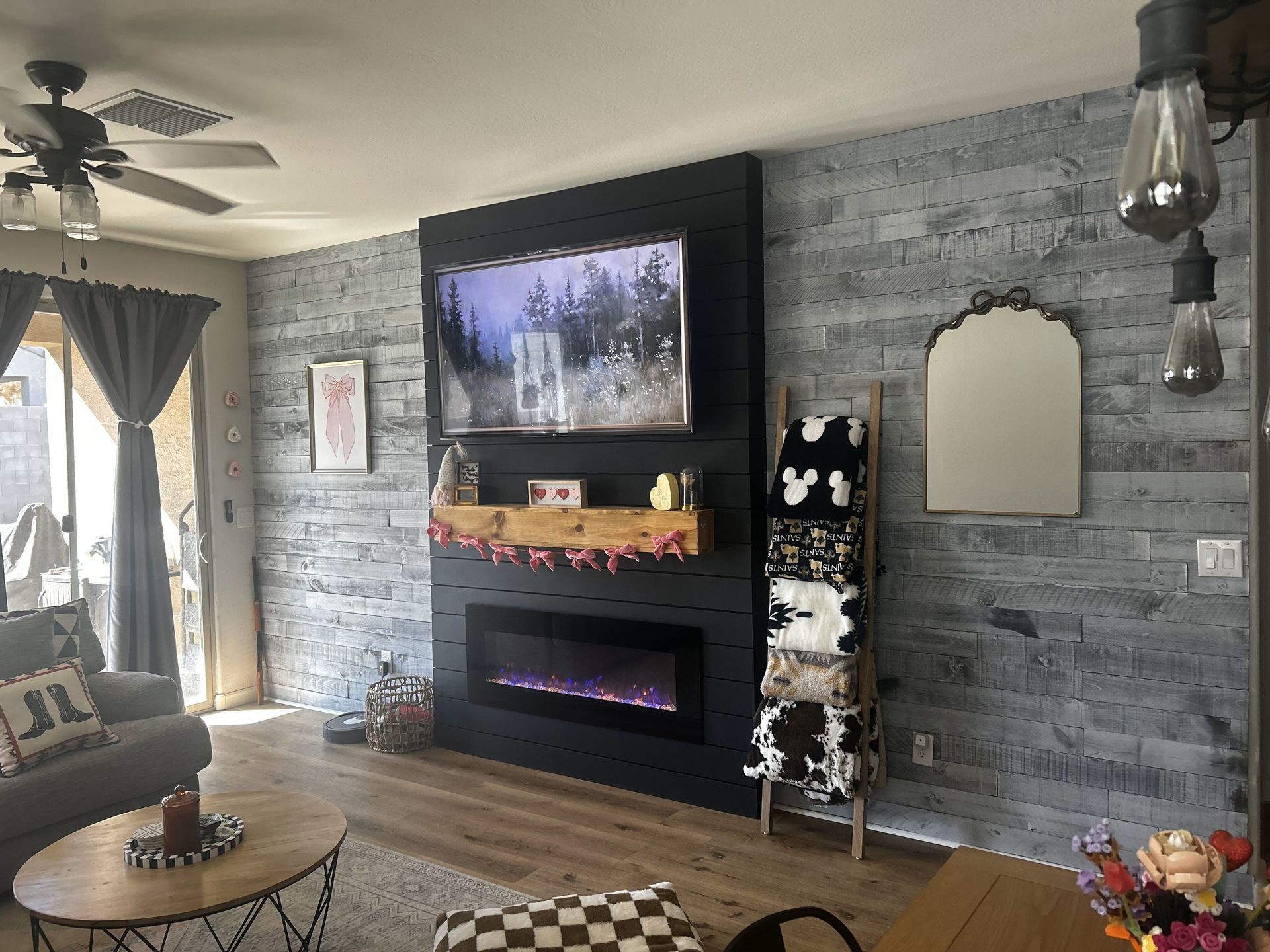 Living room with a gray shiplap accent wall, black fireplace, and TV.