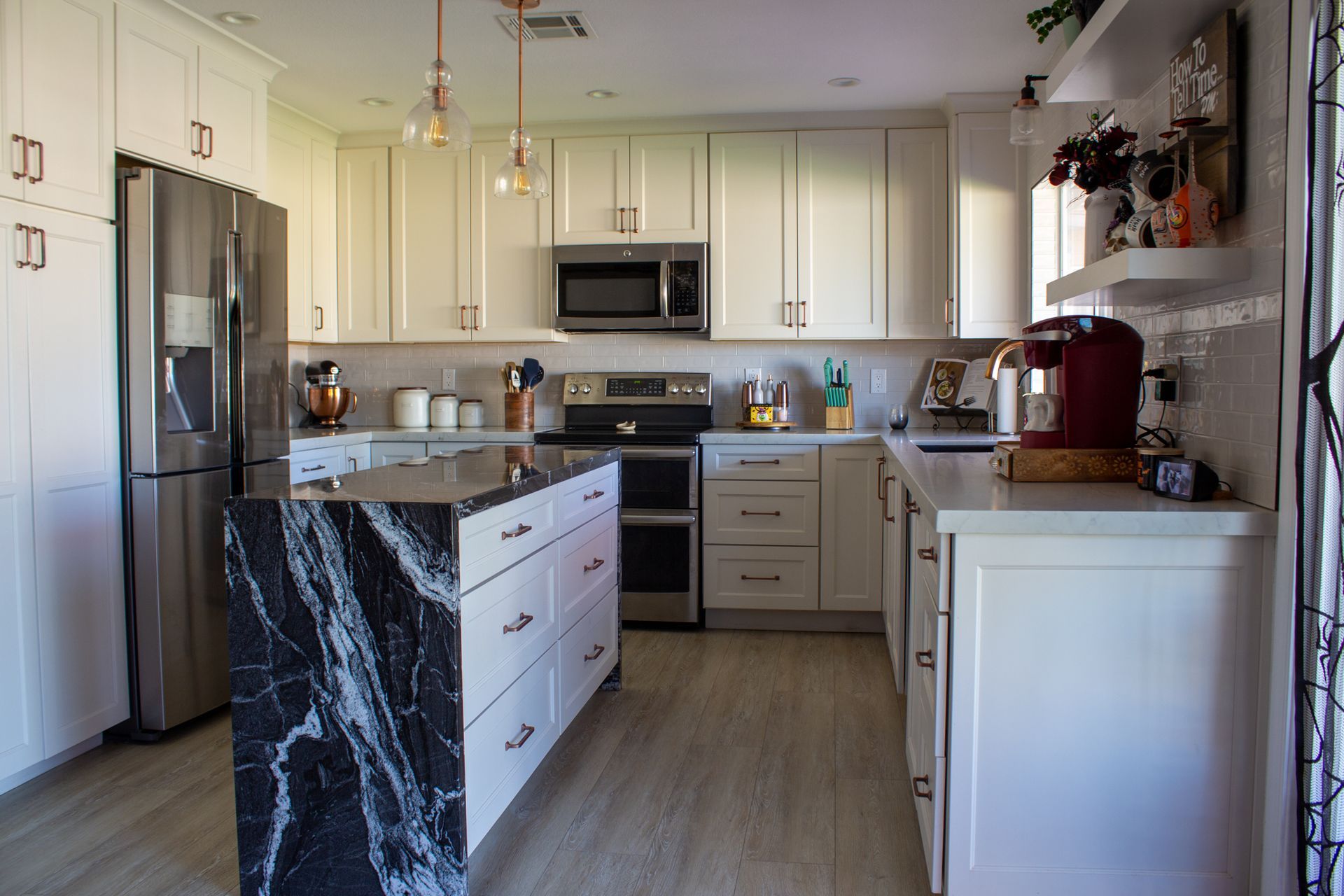 Modern kitchen with white cabinets, stainless steel appliances, and a black marble island.