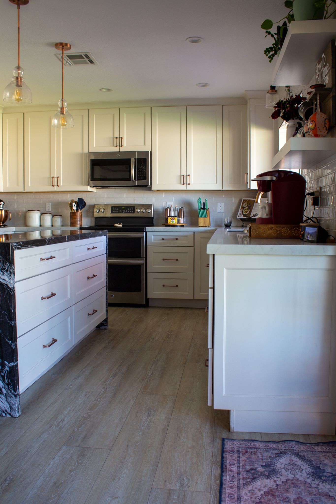 White kitchen with black granite island, stainless steel appliances, and wood floors.