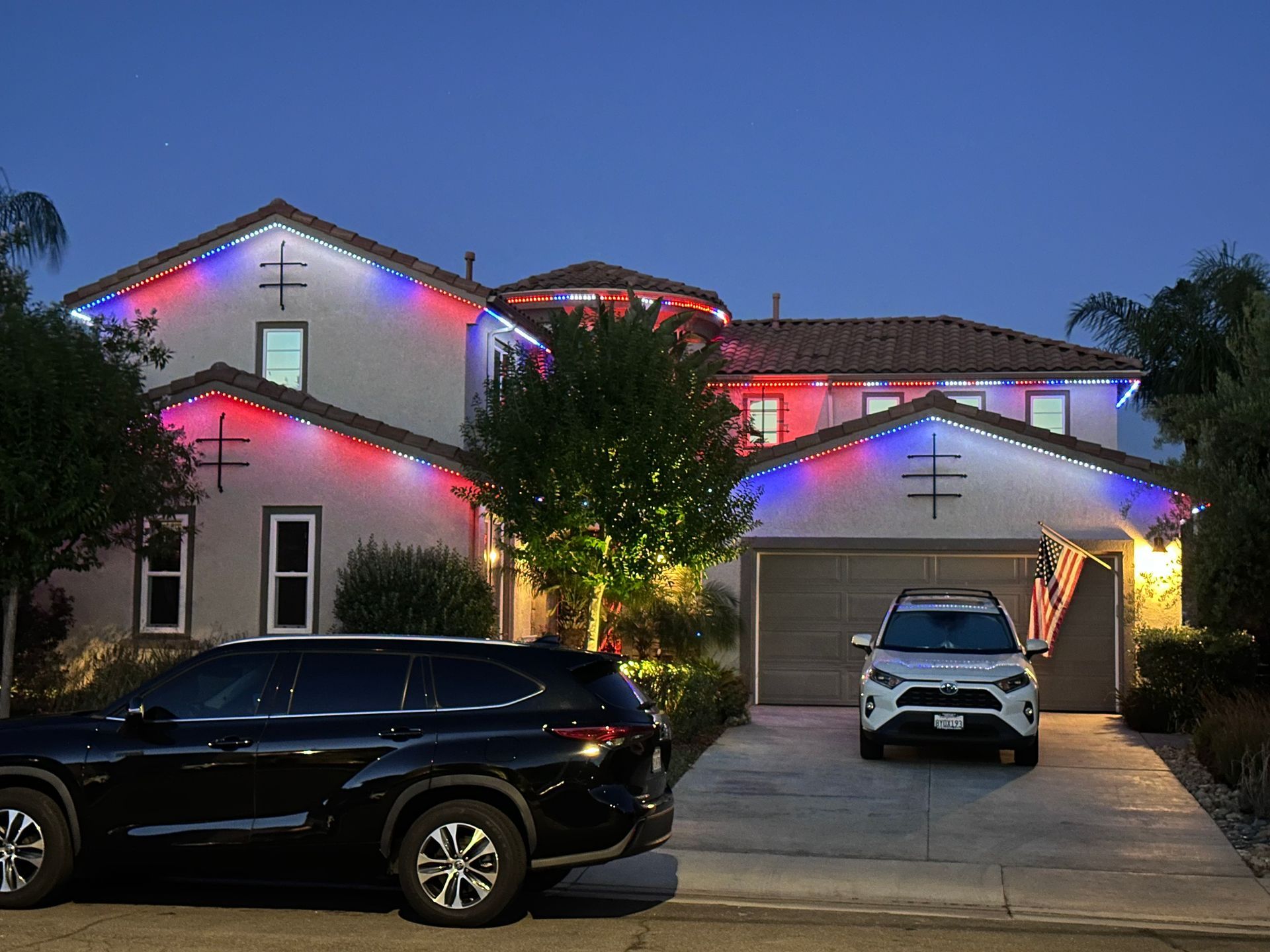 Hands arranging string lights along a wooden structure at dusk. Warm bulbs glow.