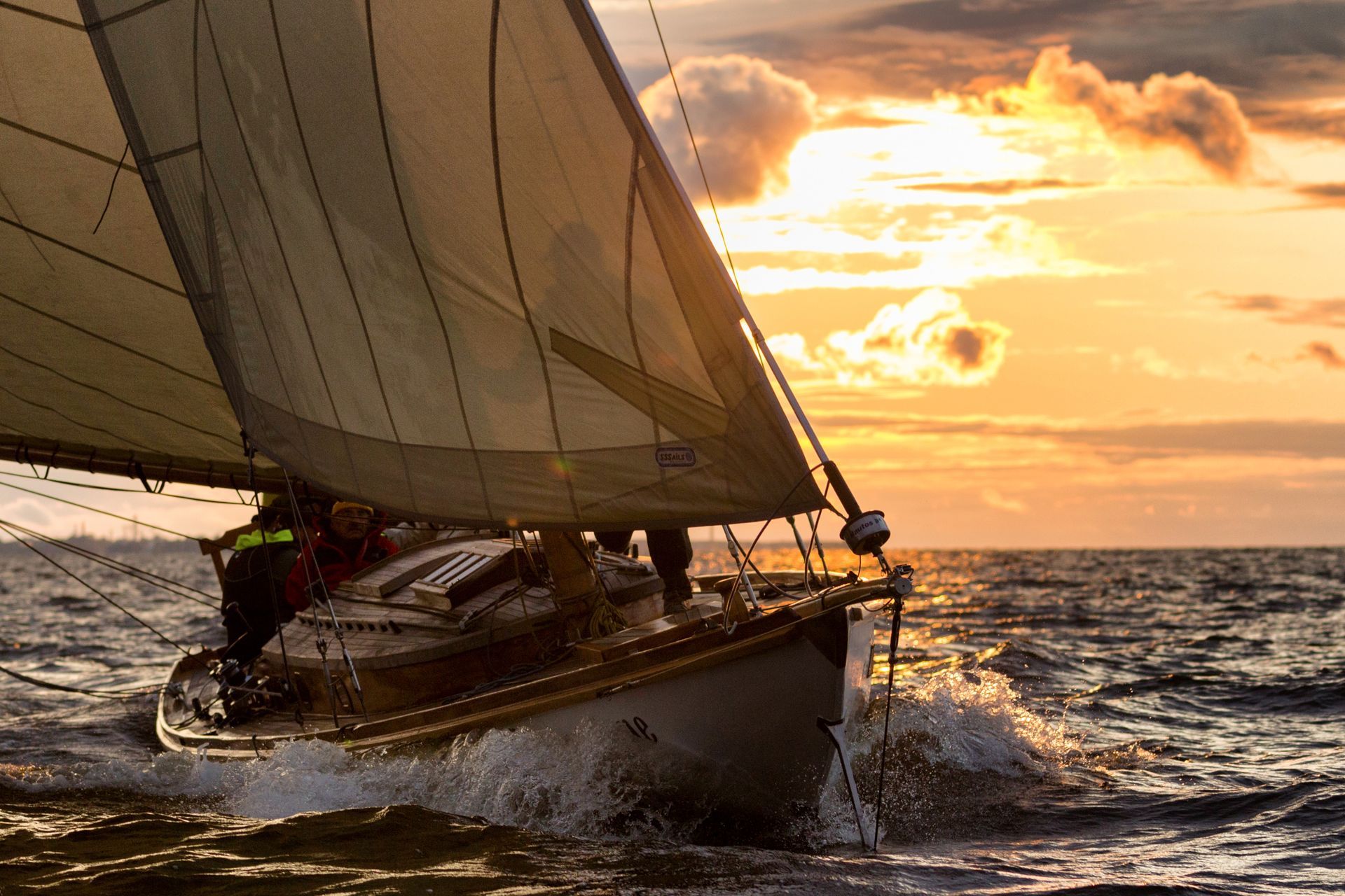 A sailboat is sailing in the ocean at sunset
