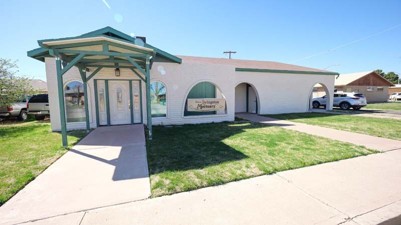 Modern single-story house with a teal carport, arched windows, and a front sidewalk in bright sunlight