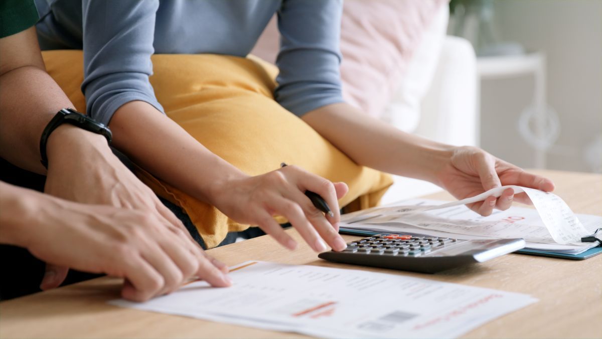 Hands using a calculator and writing on papers at a table