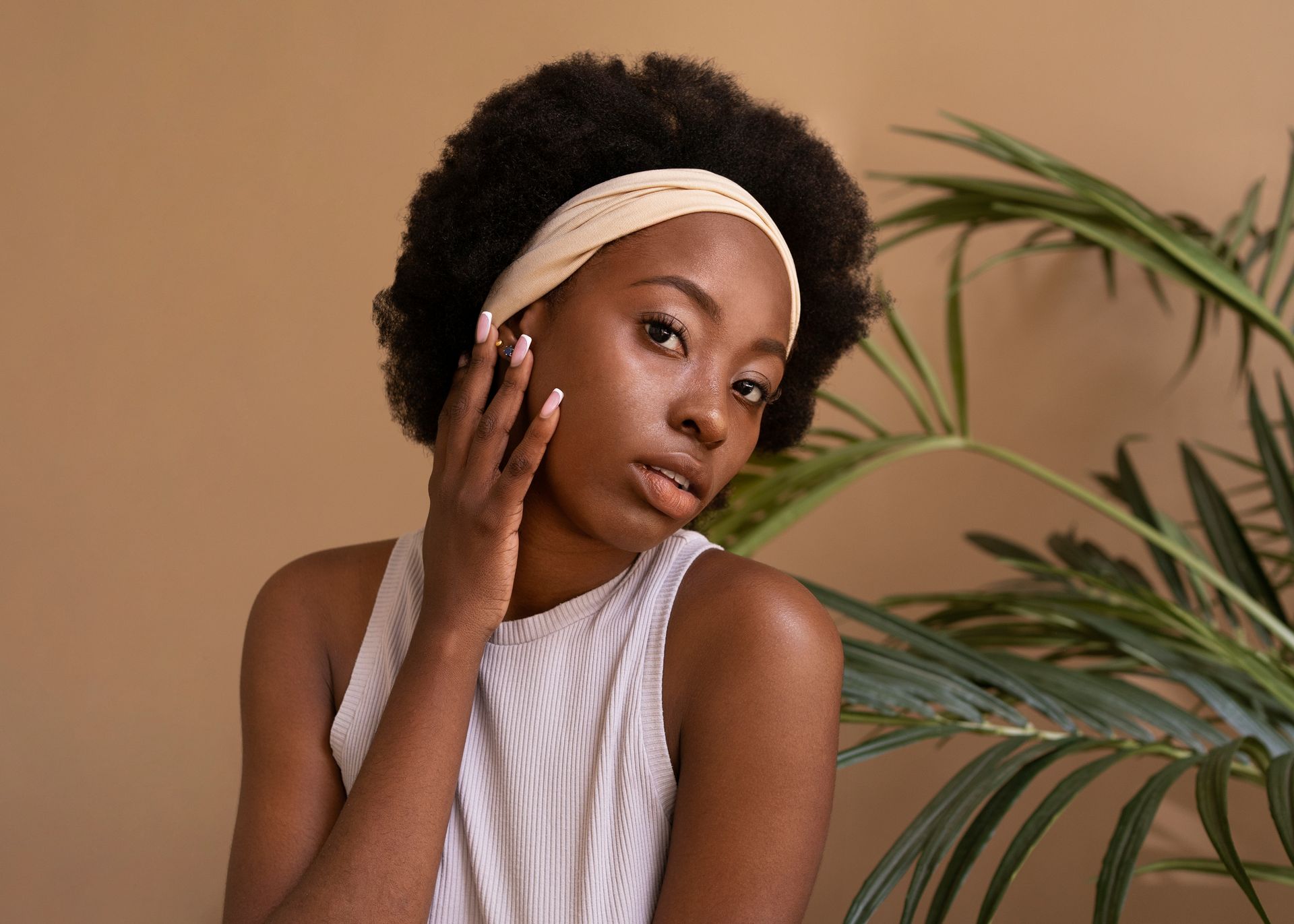 A woman wearing a headband is standing in front of a palm tree.