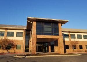 Brick building with glass windows, entrance portico, and blue sky.