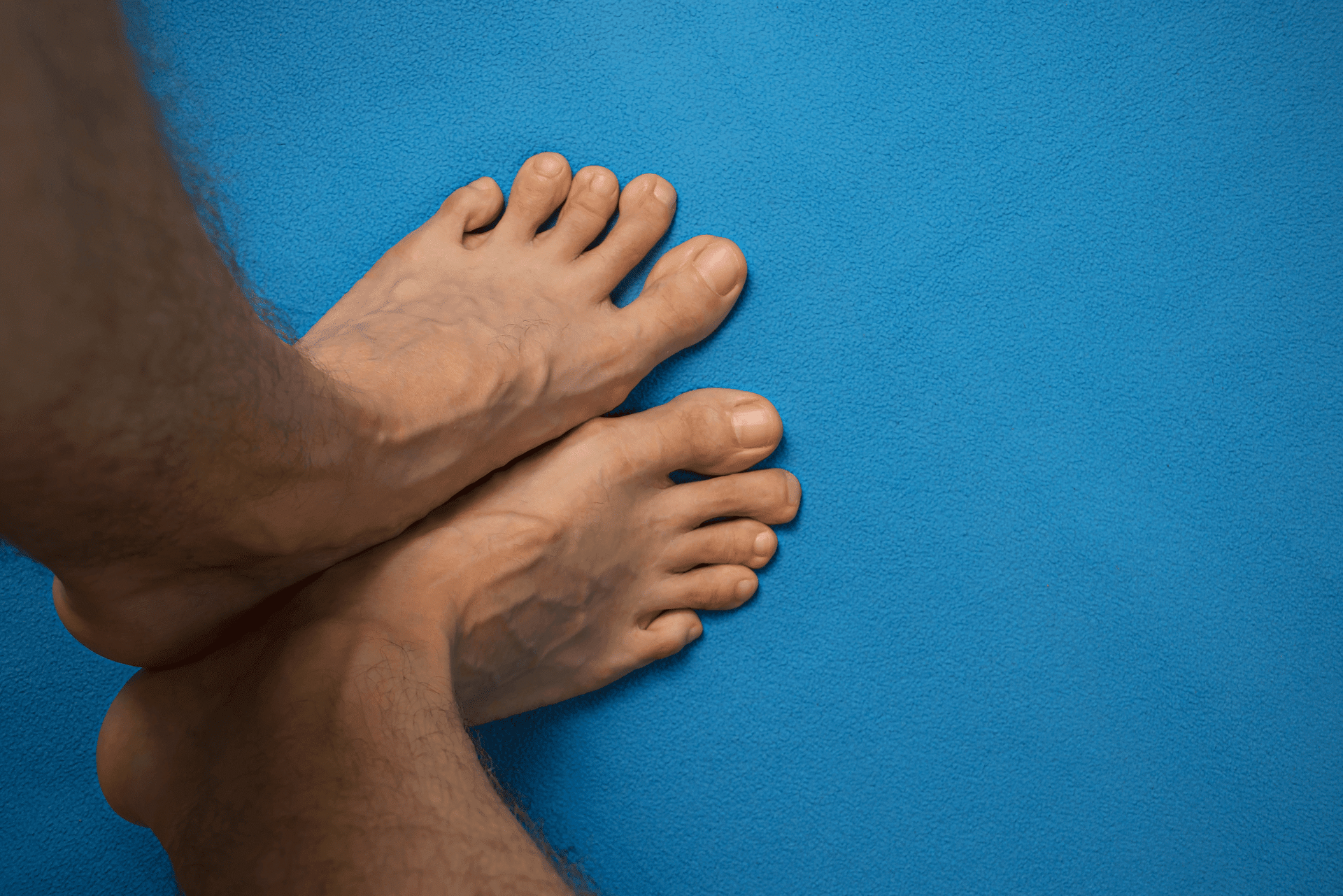 Bare feet crossed on a blue textured surface.