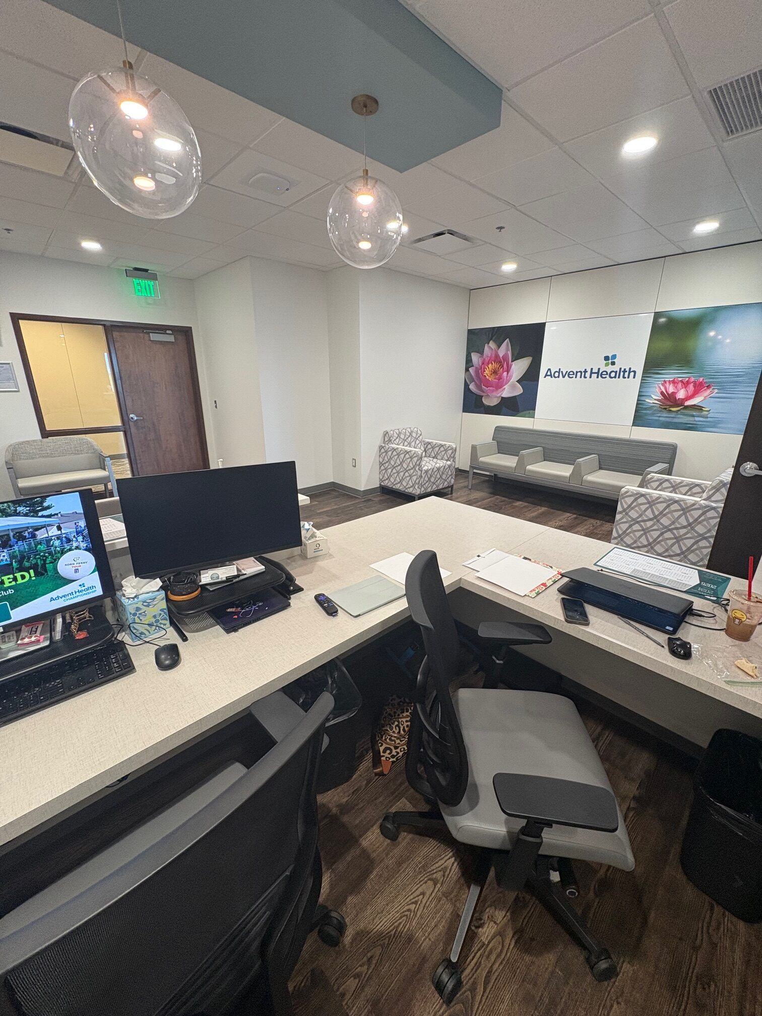 Office interior with a desk, chairs, waiting area, and decorative hanging lights.