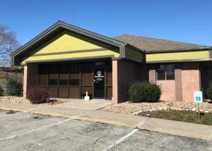 Exterior view of a one-story brick and yellow building with a handicap parking sign.