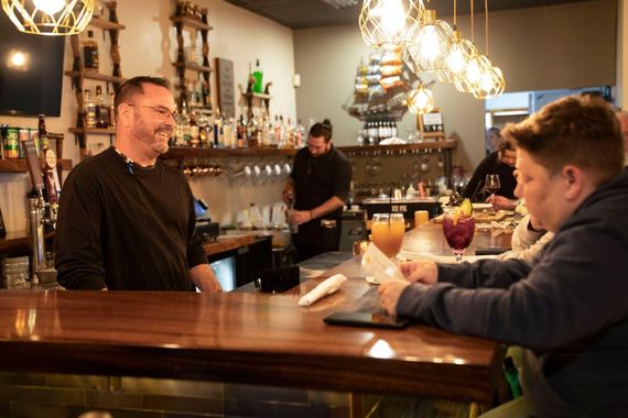 A man and a boy are sitting at a bar in a restaurant.