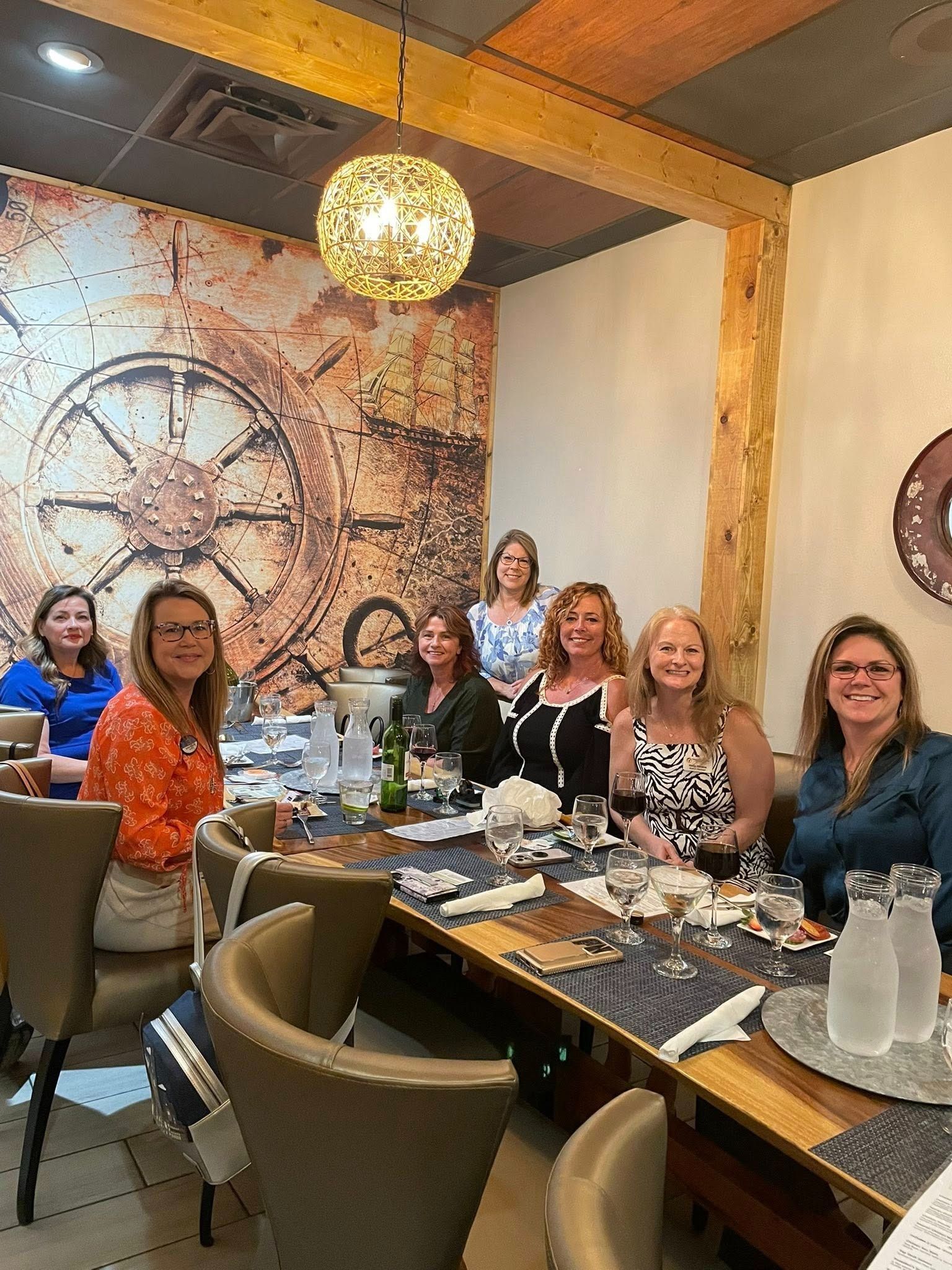 A group of women are sitting at a long table in a restaurant.